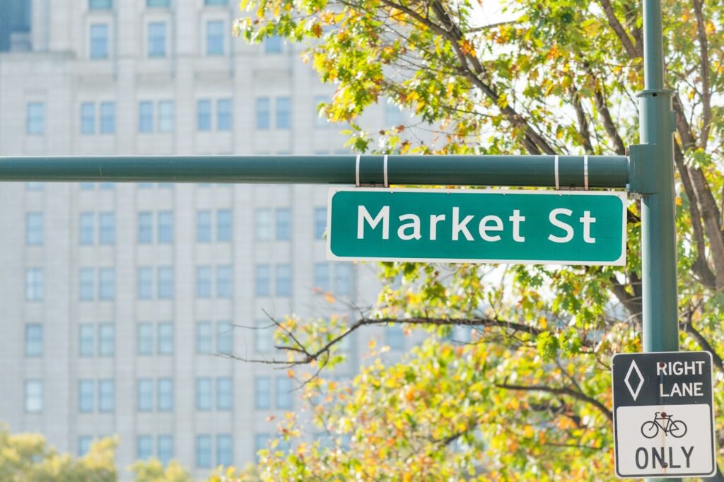 Green Market St street sign mounted on cantilever bracket extending from pole in urban setting with Right Lane bike only sign below